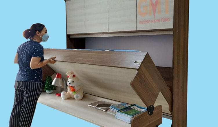 Người phụ nữ đang mở giường gấp thông minh có bàn học và tủ trên
