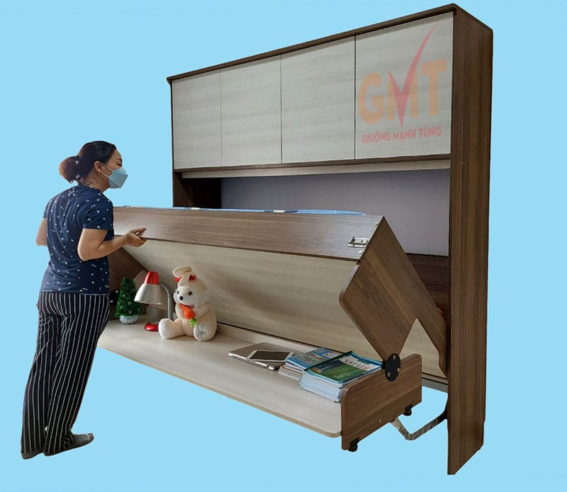 Người phụ nữ đang mở giường gấp thông minh có bàn học và tủ trên
